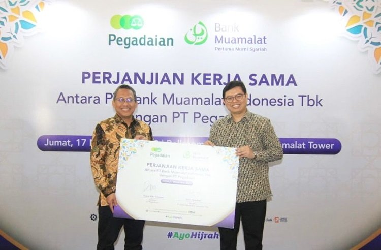 Direktur Utama PT Bank Muamalat Indonesia Tbk Indra Falatehan (kanan) dan Direktur Utama PT Pegadaian Damar Latri Setiawan (kiri) memperlihatkan mockup Perjanjian Kerja Sama (PKS) pendaftaran porsi haji reguler di Muamalat Tower, Jakarta, Jum'at, 17 November 2023. (Foto: Urbancity.co.id/Pool/Dok. Bank Muamalat)