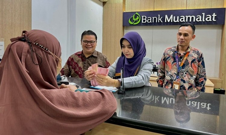 Branch Manager Bank Muamalat Langsa Affan Syuaidi (kanan) bersama Branch Operations Service Manager Didi Mariadi (kiri) menyaksikan nasabah yang sedang bertransaksi di Kantor Cabang Langsa, Aceh, Kamis, 27 Maret 2025.